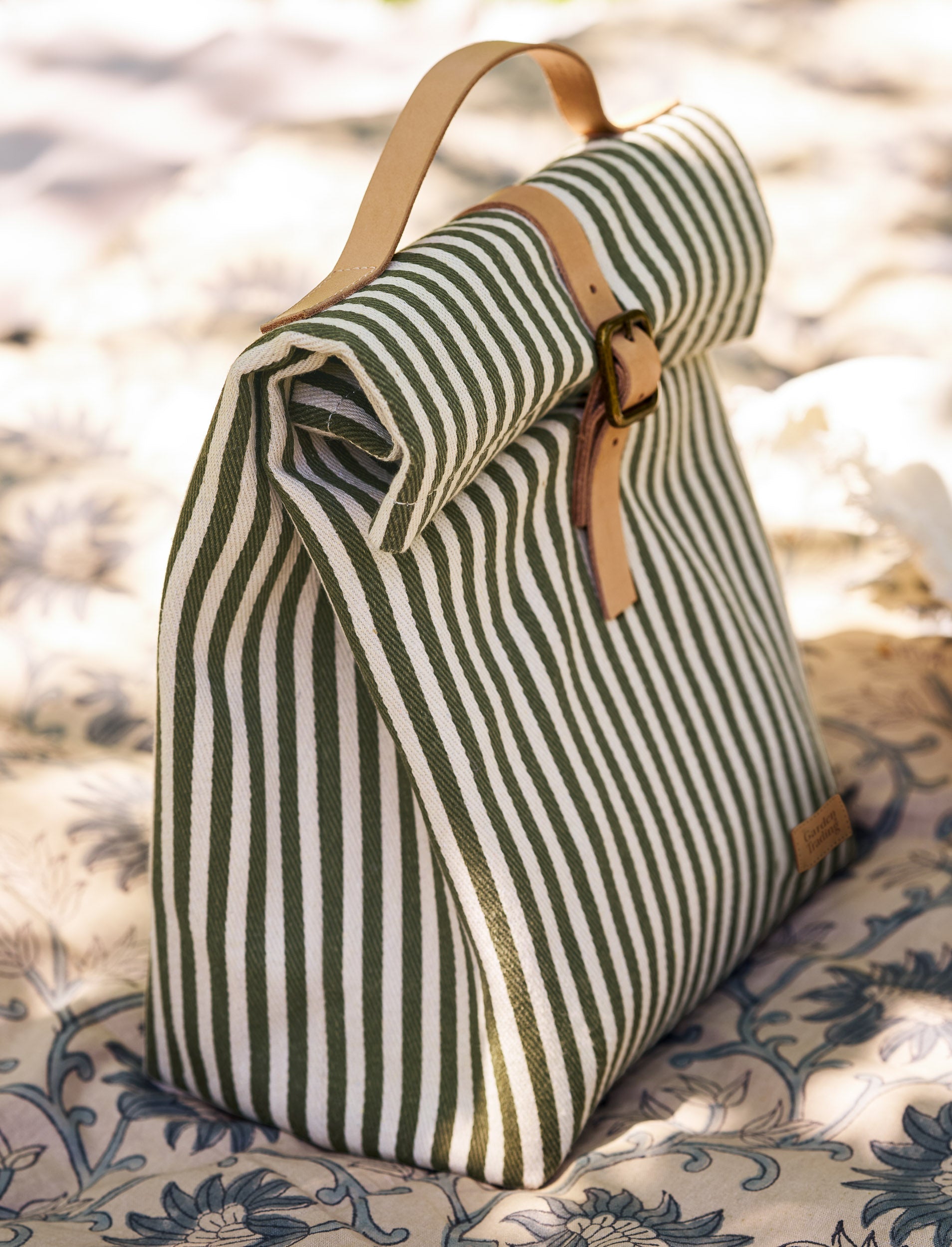 Striped lunch bag with leather straps on a patterned surface