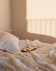 A relaxed neutral coloured bedroom at sunset with a textured white bedspread and pillow.