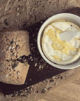 Stoneware Cheese Baker Set on wooden paddle with melted brie and crusty bread.