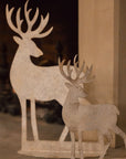 2 white reindeer decorations on a fireplace.