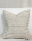 Cream embroidered cushion on a white sofa.