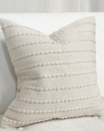 Cream embroidered cushion on a white sofa.