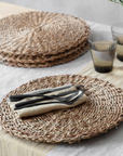 Set of 4 woven placemats, with three in a stack and one separately with napkins and cutlery.