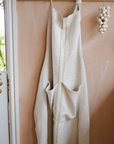 Cream striped linen apron hanging on wooden hooks.
