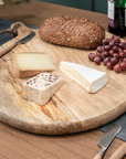 Round wooden serving board with jute rope loop, with cheese, bread and grapes on.
