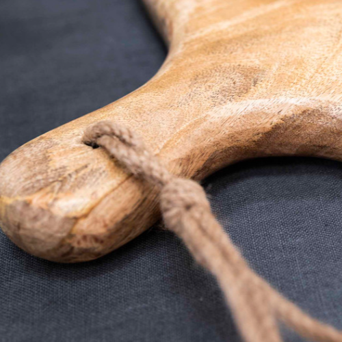 Close up of handle on round wooden serving board with jute rope loop.