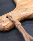 Close up of handle on round wooden serving board with jute rope loop.