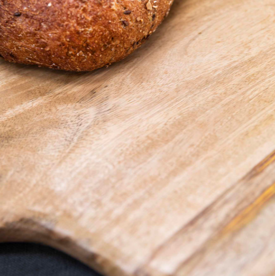 Close up of round wooden serving board with bread on.
