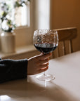 textured red wine glass in a dimly lit kitchen.