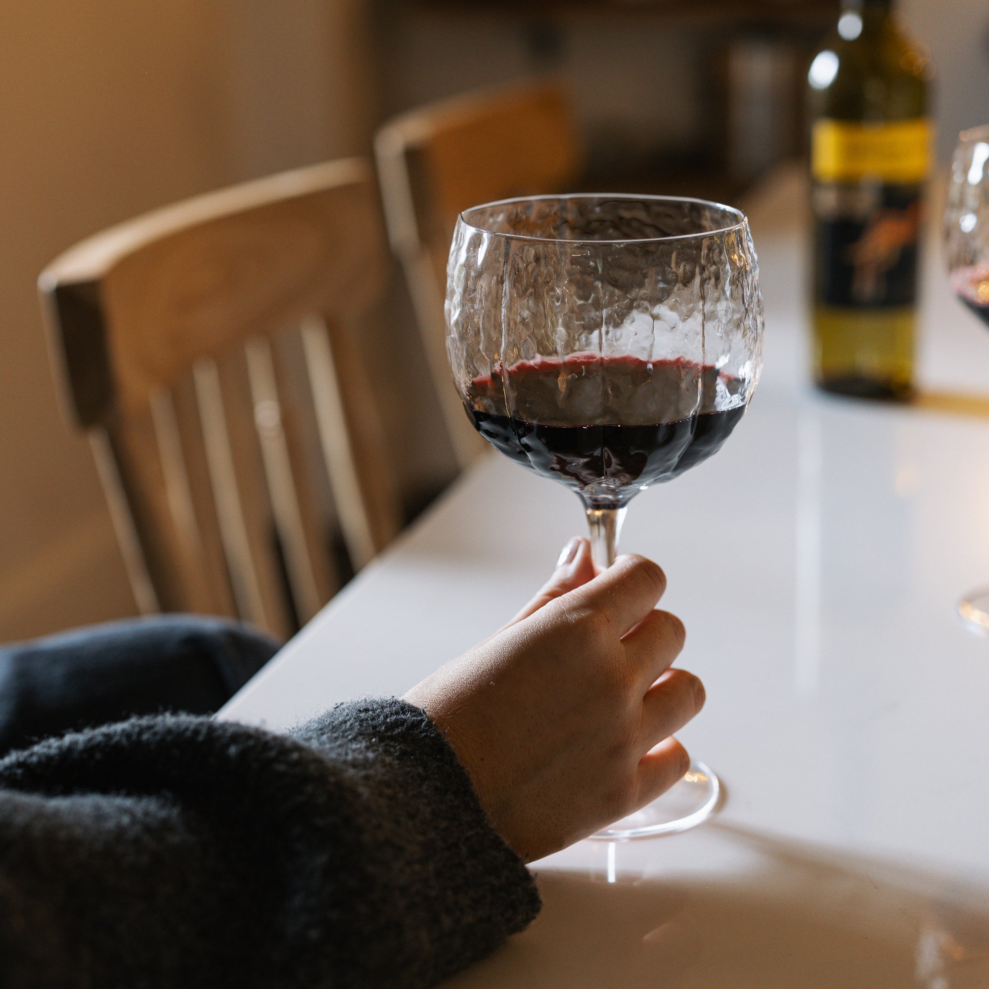 textured red wine glass in dimly lit kitchen.