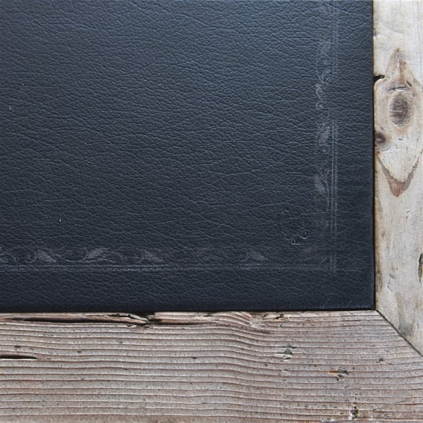 Close up of black top on reclaimed wood writing desk.