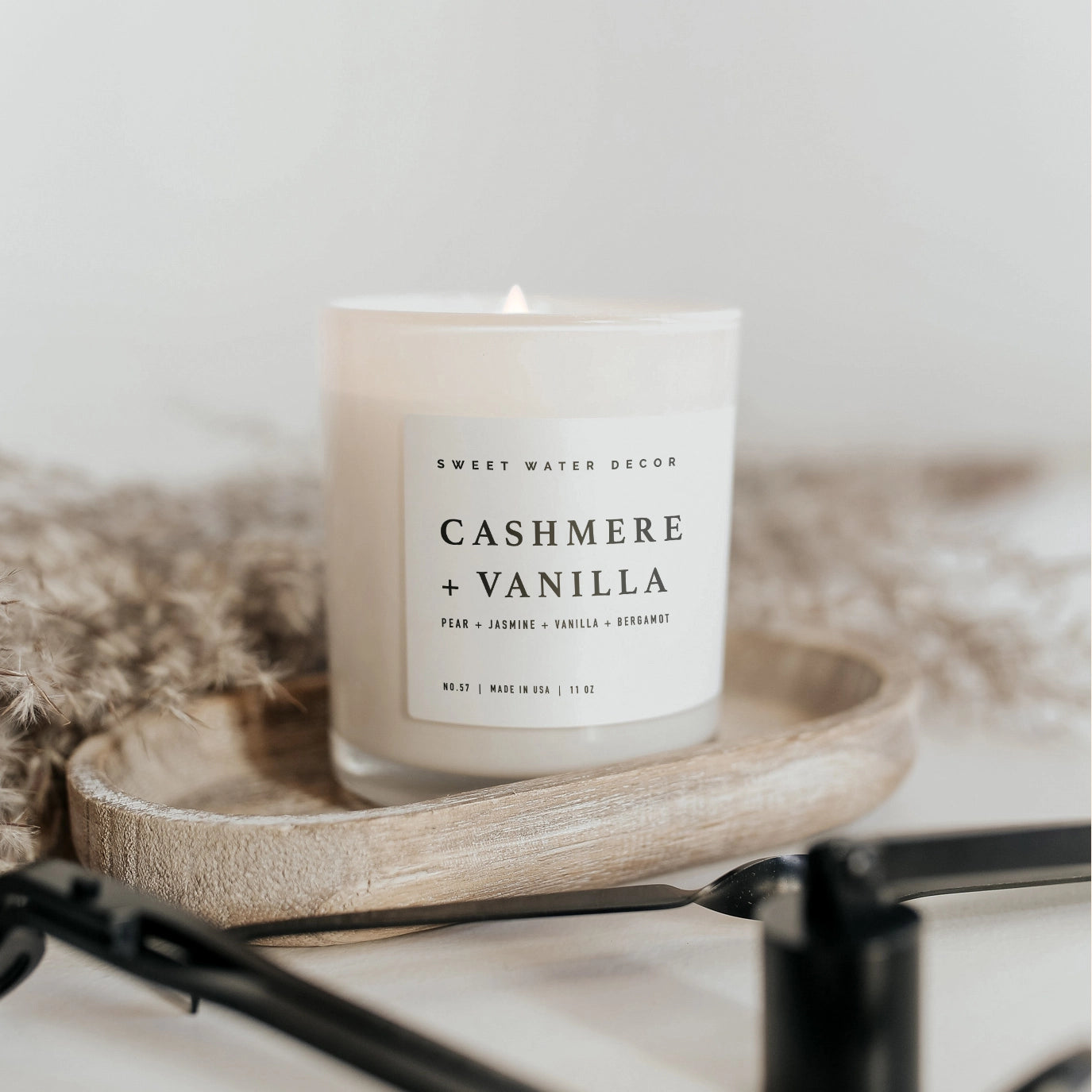 Cashmere and vanilla soy candle in white jar on wooden tray.