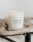 Cashmere and vanilla soy candle in white jar on wooden tray.