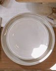 white ceramic dinner plate on wooden table with white table runner.
