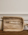 Wooden shovel tray on side against a wall.