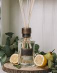 Home fragrance citrus verbena reed diffuser with lemons and greenery.