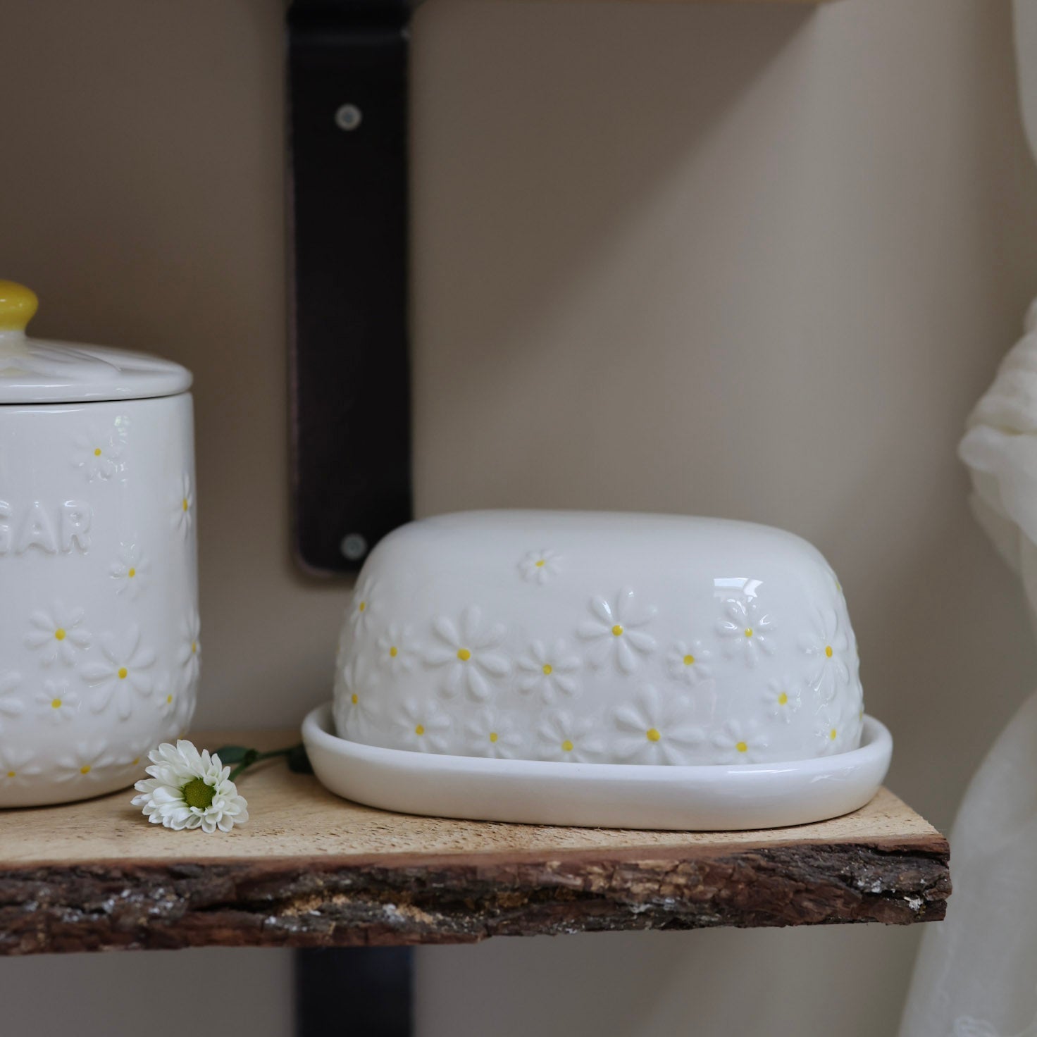 Daisy Embossed Butter Dish on wooden shelf with daisy flower.