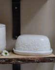 Daisy Embossed Butter Dish on wooden shelf with daisy flower.