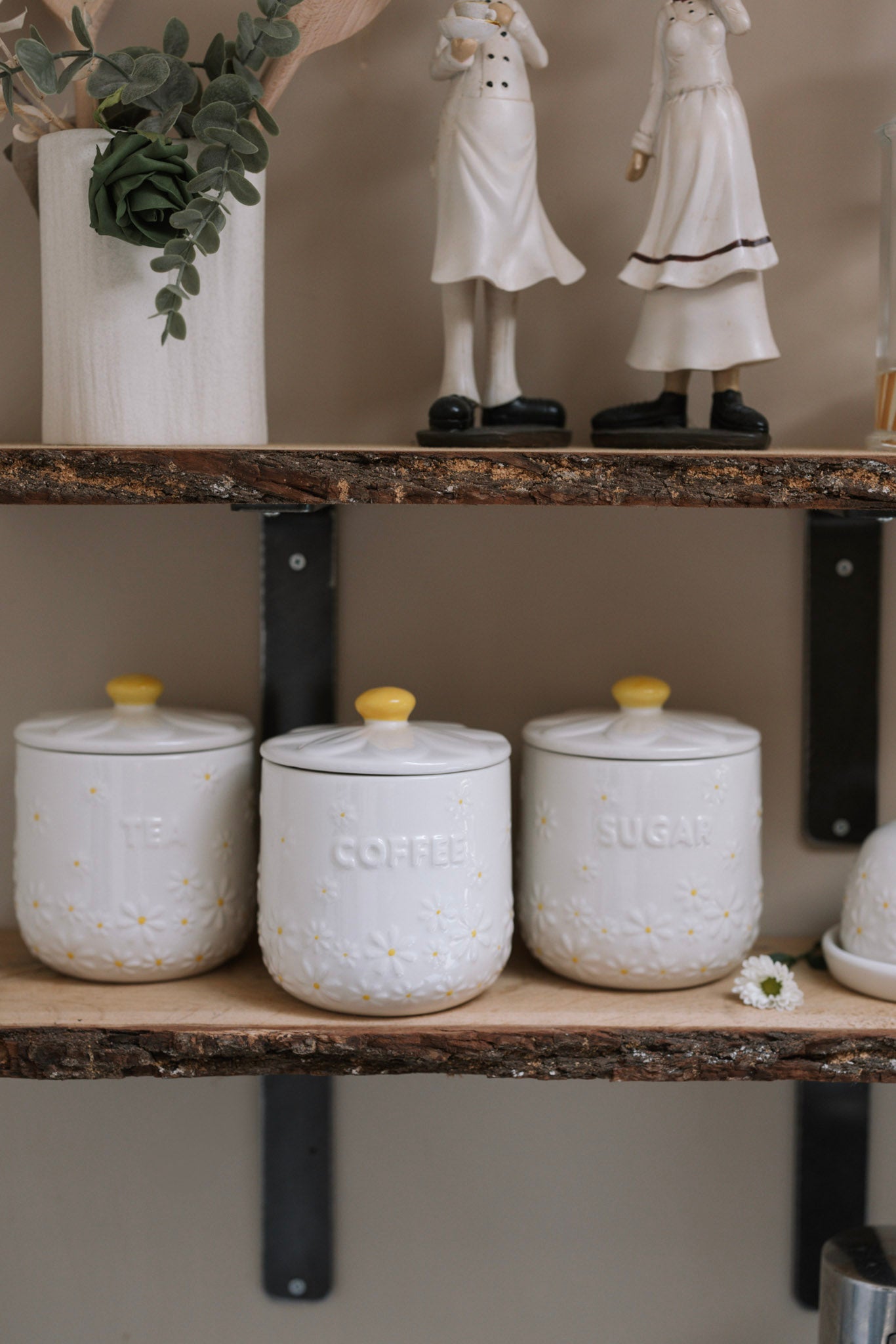 Daisy Tea coffee sugar canisters on wooden shelf with ceramic decorations