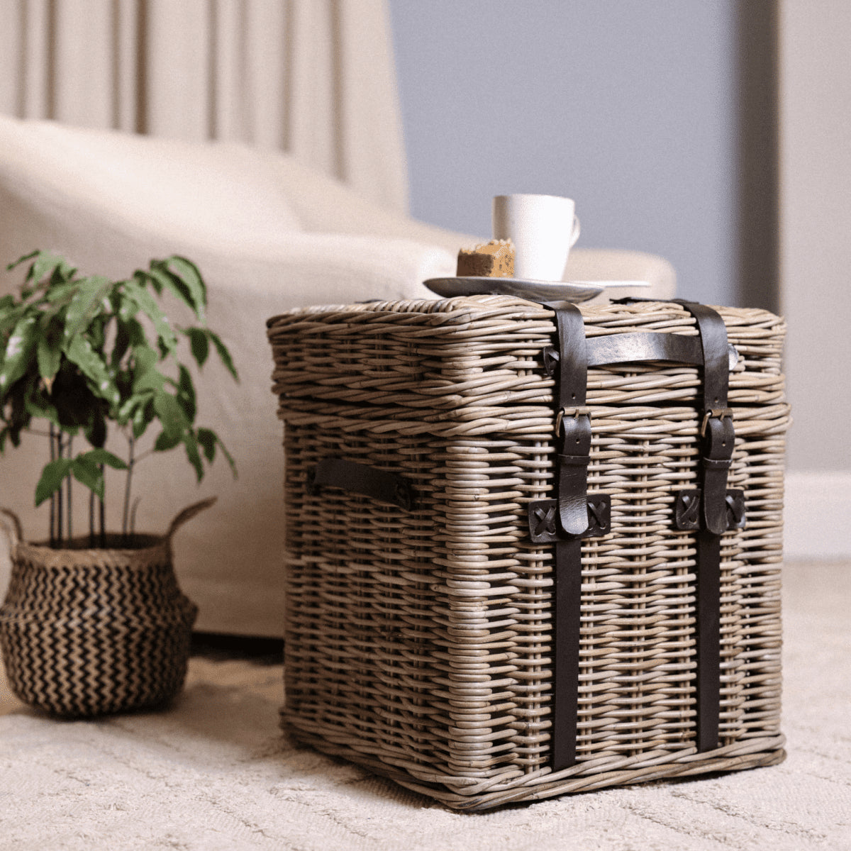 Wicker basket table with coffee and cake on top.