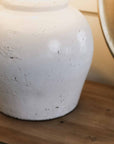 Close up of distressed white lamp base on wooden console.