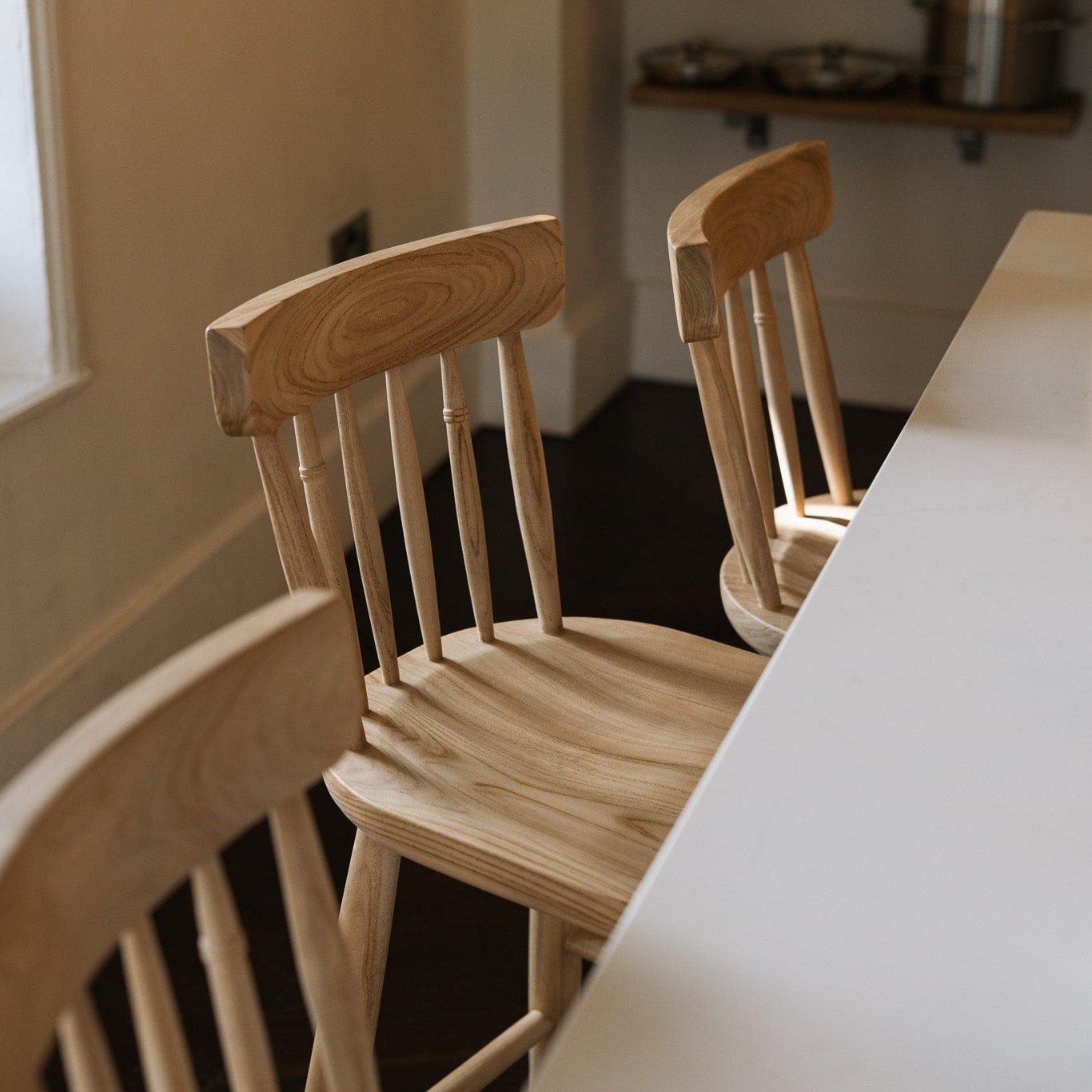 Three Farmhouse Bar Stools With Backs in dark wood kitchen with white island.