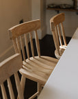 Three Farmhouse Bar Stools With Backs in dark wood kitchen with white island.