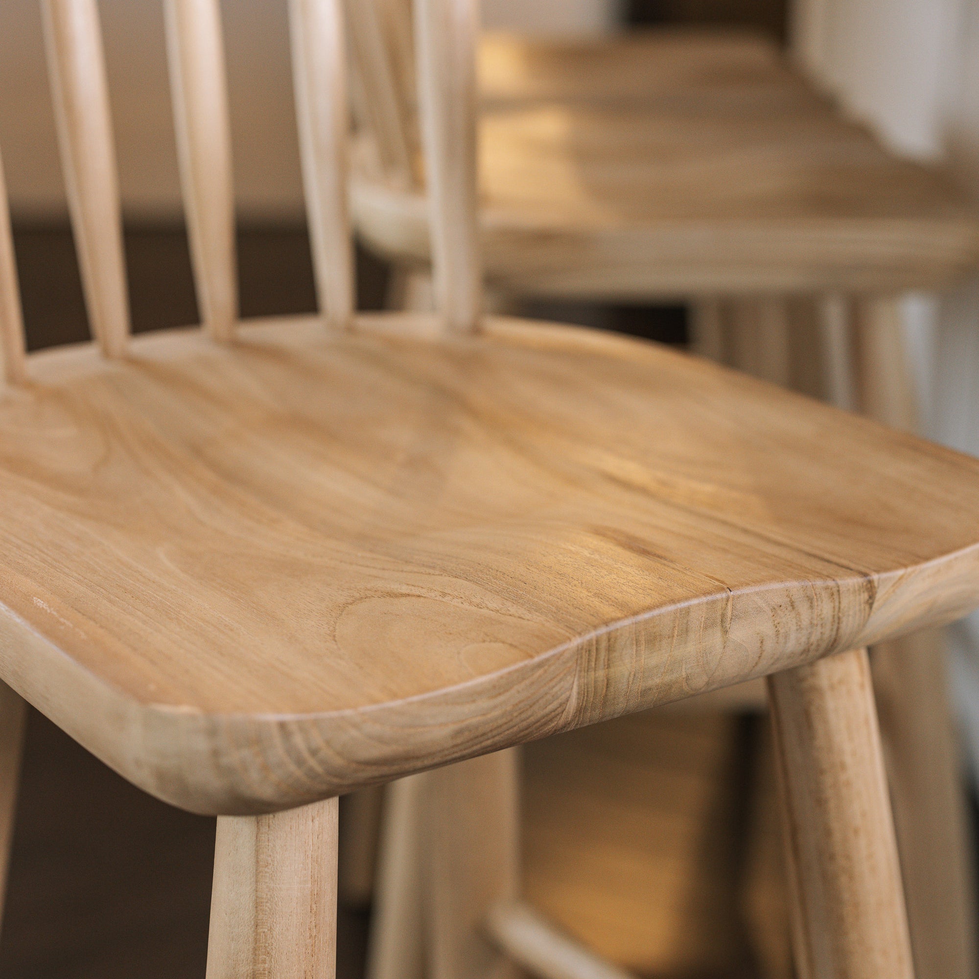 The seat of a wooden farmhouse bar stool with back.