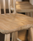 The seat of a wooden farmhouse bar stool with back.