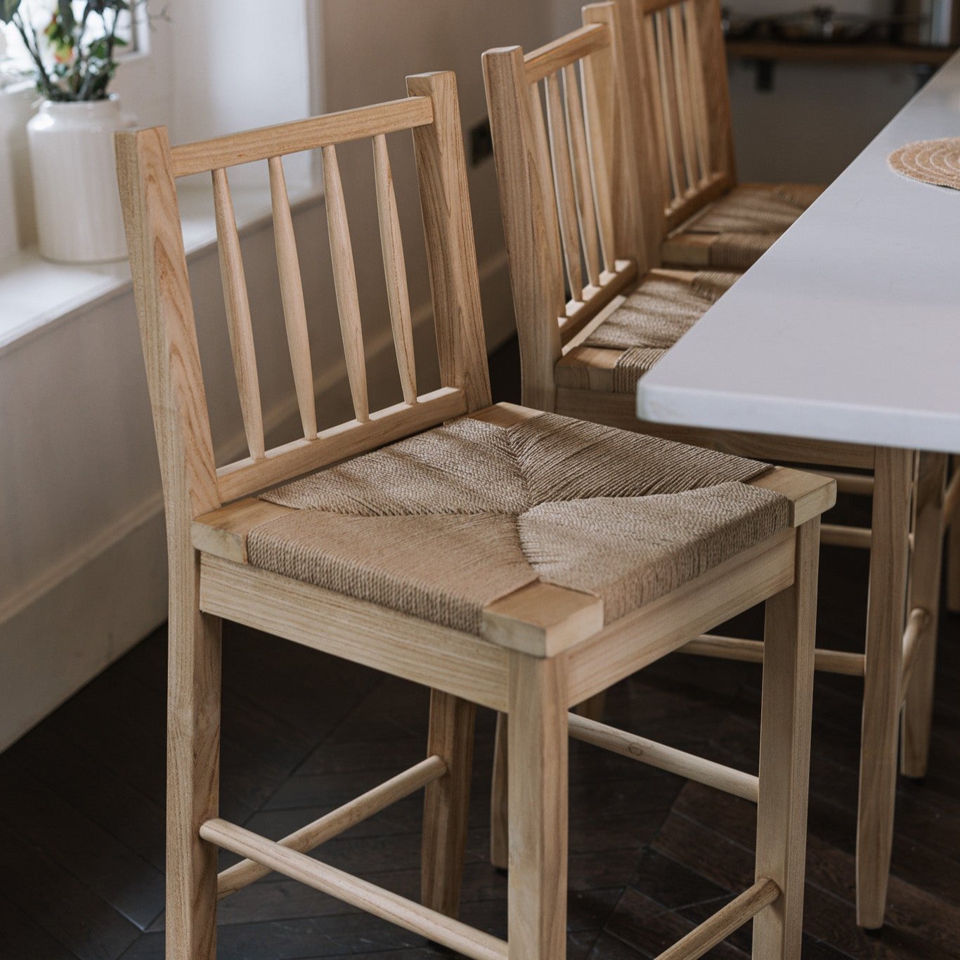 Farmhouse Rattan Bar Stool in kitchen with dark wood floor.