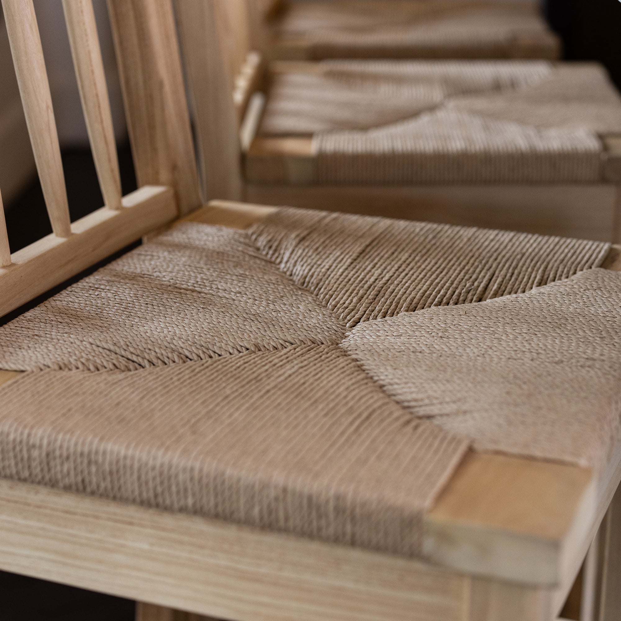 Close up shot of the Farmhouse Rattan Bar Stool in kitchen with dark wood floor.