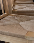 Close up shot of the Farmhouse Rattan Bar Stool in kitchen with dark wood floor.