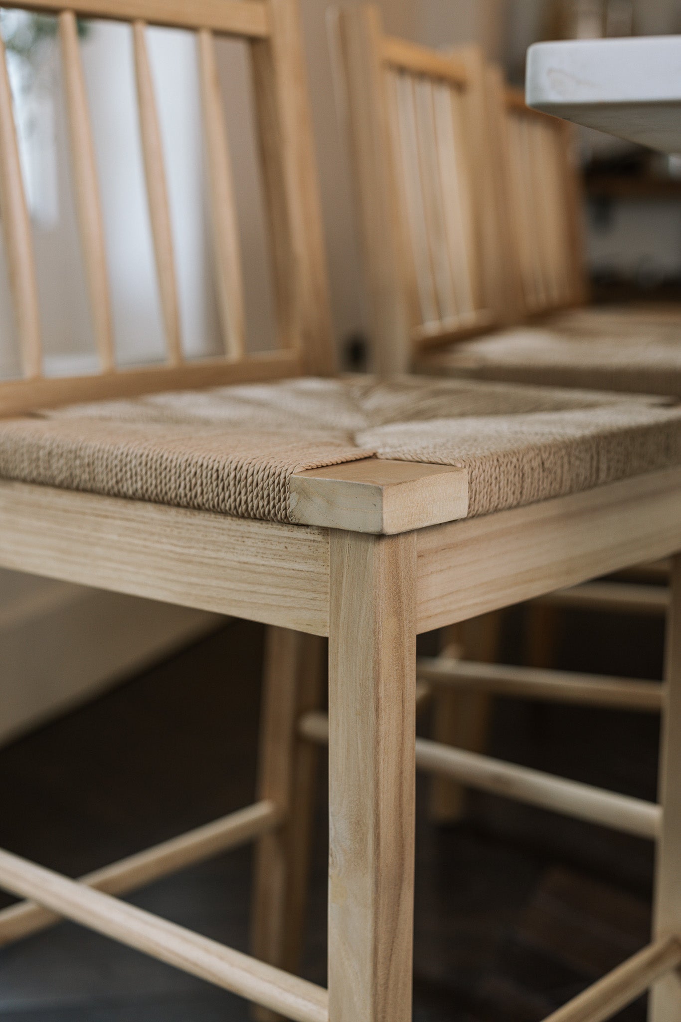 Close up photo of Farmhouse Rattan Bar Stool seat in kitchen with dark wood floor.