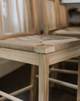 Close up photo of Farmhouse Rattan Bar Stool seat in kitchen with dark wood floor.