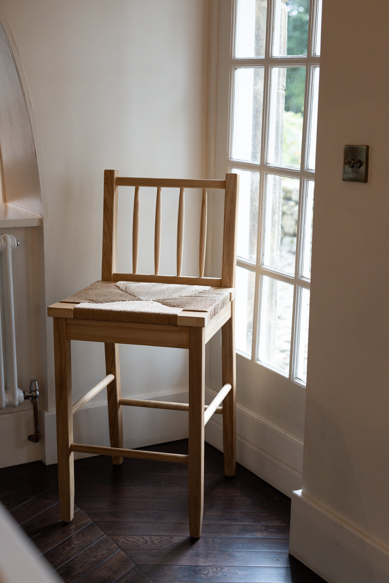 Farmhouse Rattan Bar Stool in kitchen with dark wood floor by the window.