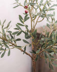 Close up of artificial leaves and olives on faux olive tree.