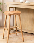 Backless wooden bat stool in front of breakfast bar with coffee cup.