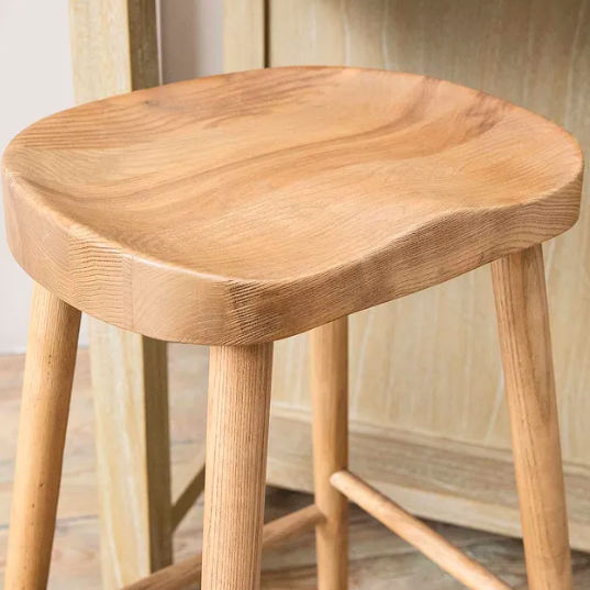 Close up of curved seat on backless wooden bar stool.