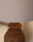 Close up of neutral linen lamp shade with wooden base.