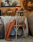 French style wooden dining chair at a table with autumnal decorations and an orange throw.