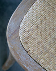 Close up of wicker seat on white washed wooden dining chair.