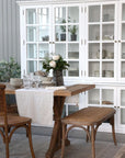 Large white armoire cabinet with glass doors filled with kitchen crockery, next to a dining table.