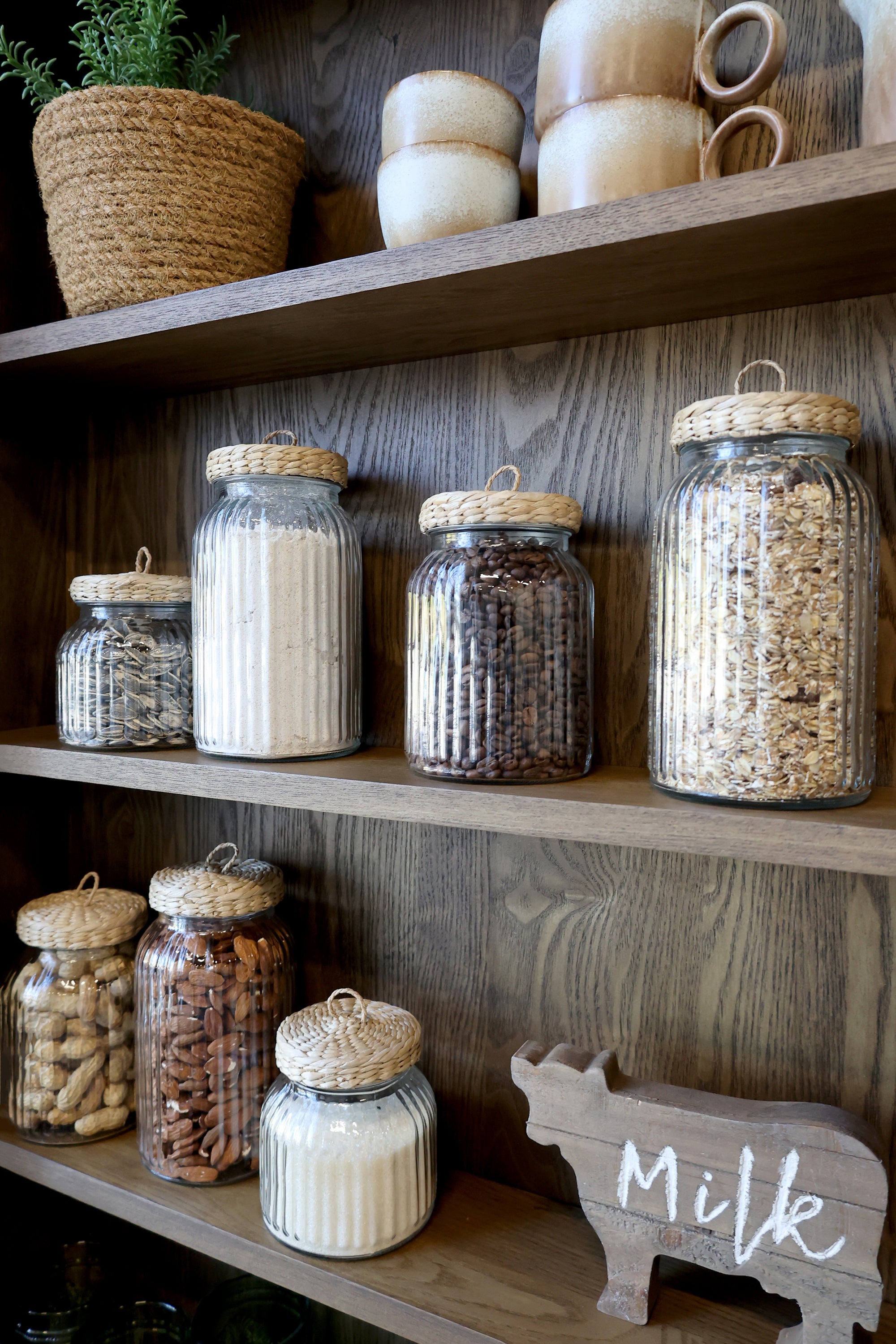 Close up of shelving and pantry items on natural wooden wall cabinet.