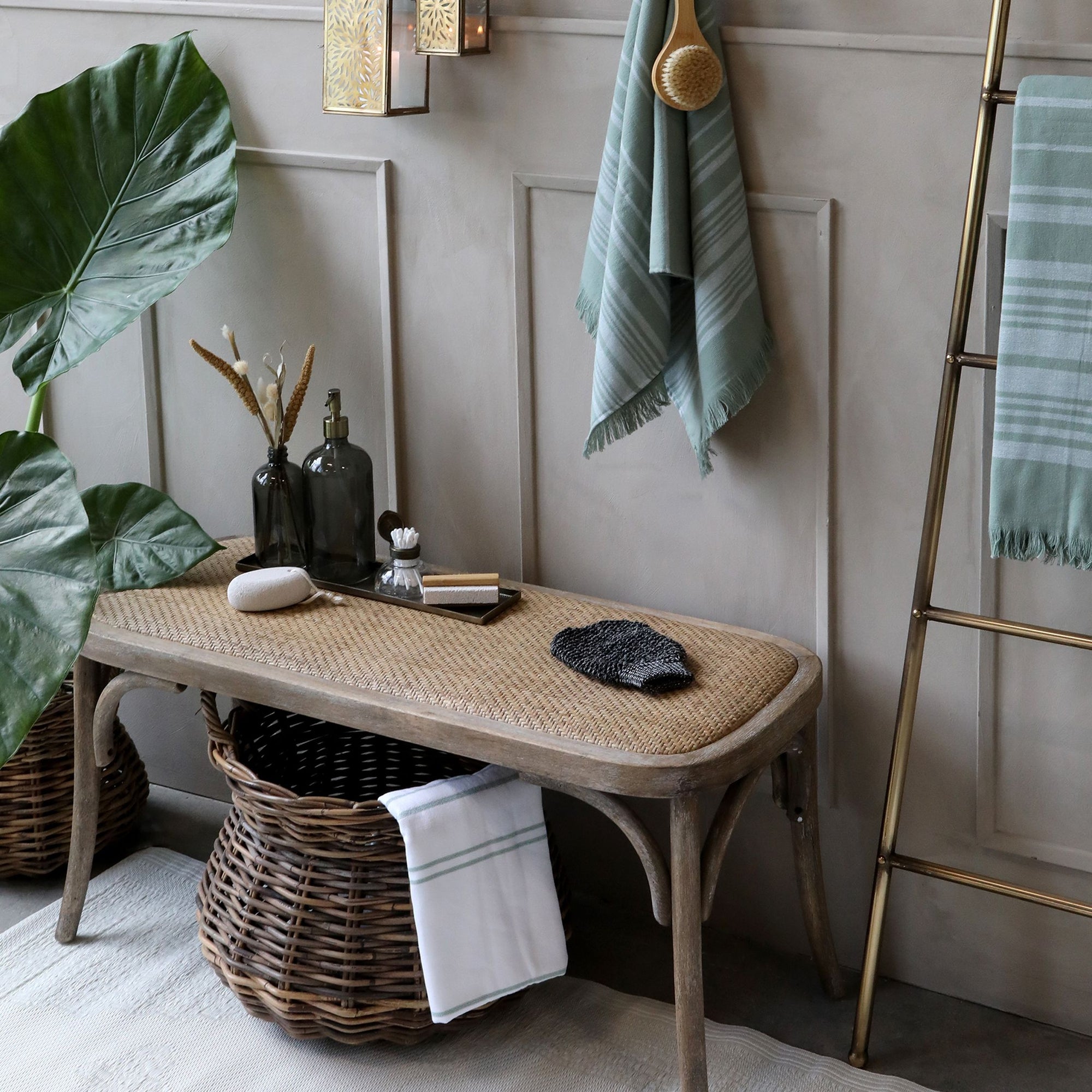 Rattan bench in neutral room with baskets and plants.