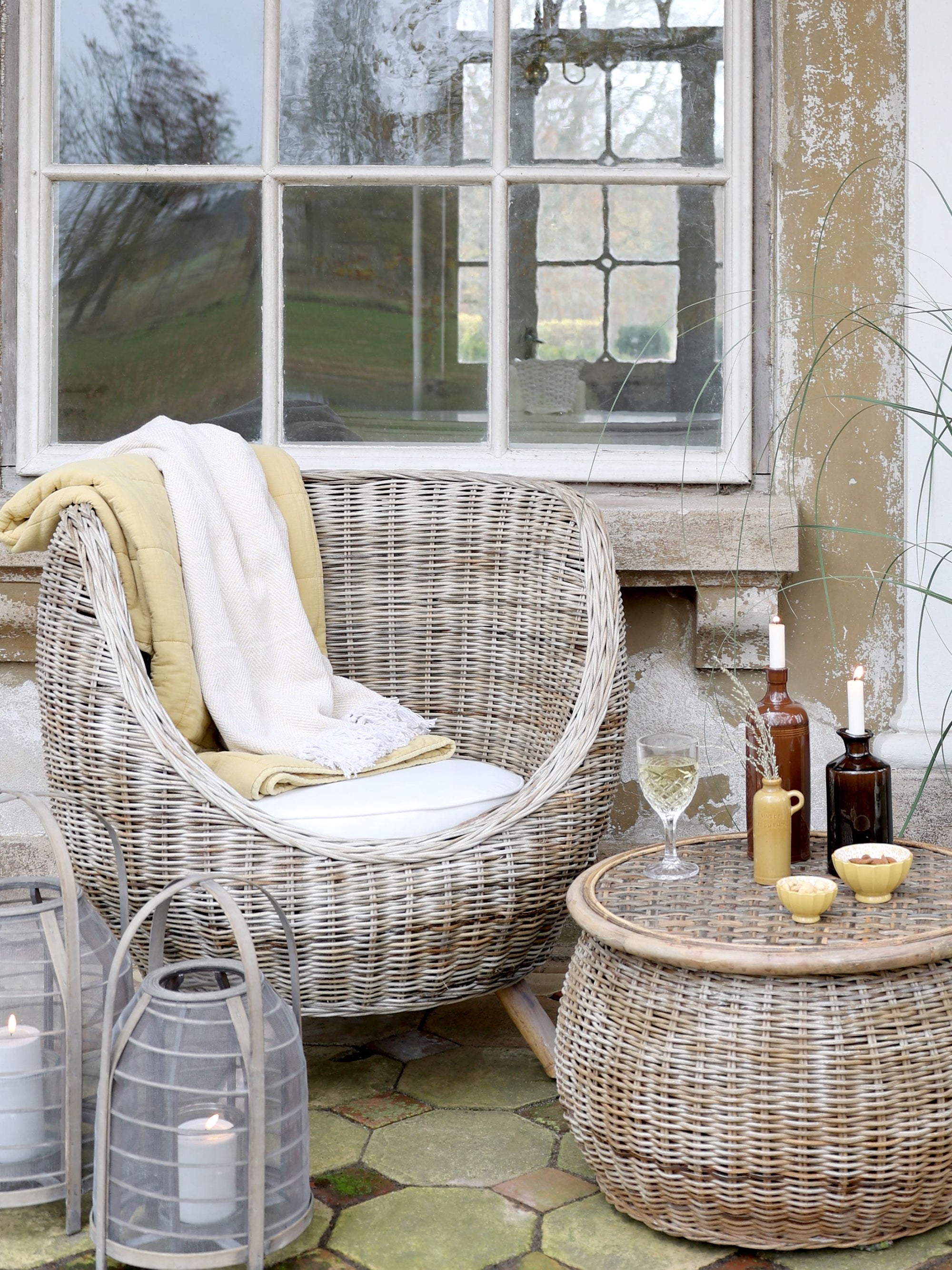 rattan armchair and table with wine and lanterns.