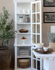 White display cabinet with glass doors open and kitchen accessories on the shelves.