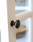 Close up of door knob on white display cabinet.