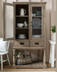 Glass Display Cabinet with crockery and a basket of flowers.
