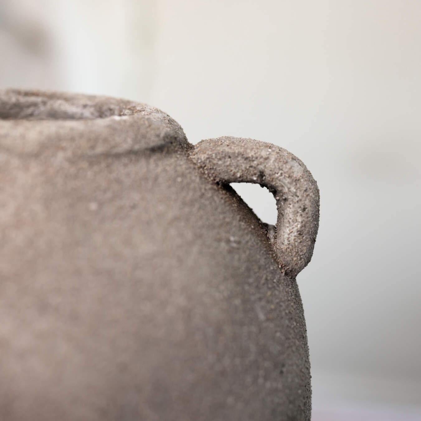 Close up of small handle on textured grey vase.
