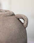 Close up of small handle on textured grey vase.